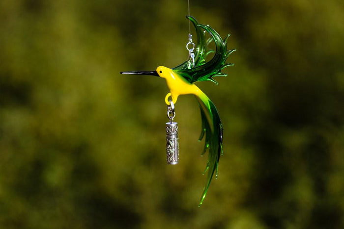 Bee eater glass bird with a sterling silver keepsake urn pendant against a soft green background.