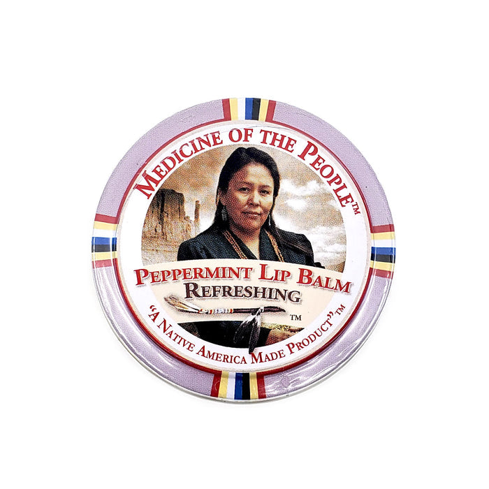 A round container of 'Medicine of the People' Peppermint Lip Balm with a label featuring a portrait of a woman and peppermint imagery against a background of multiple colors.
