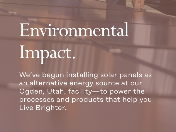 Text on a blurred background showing solar panels. The text reads: "Environmental Impact. We’ve begun installing solar panels as an alternative energy source at our Ogden, Utah, facility—to power the processes and products that help you Live Brighter.