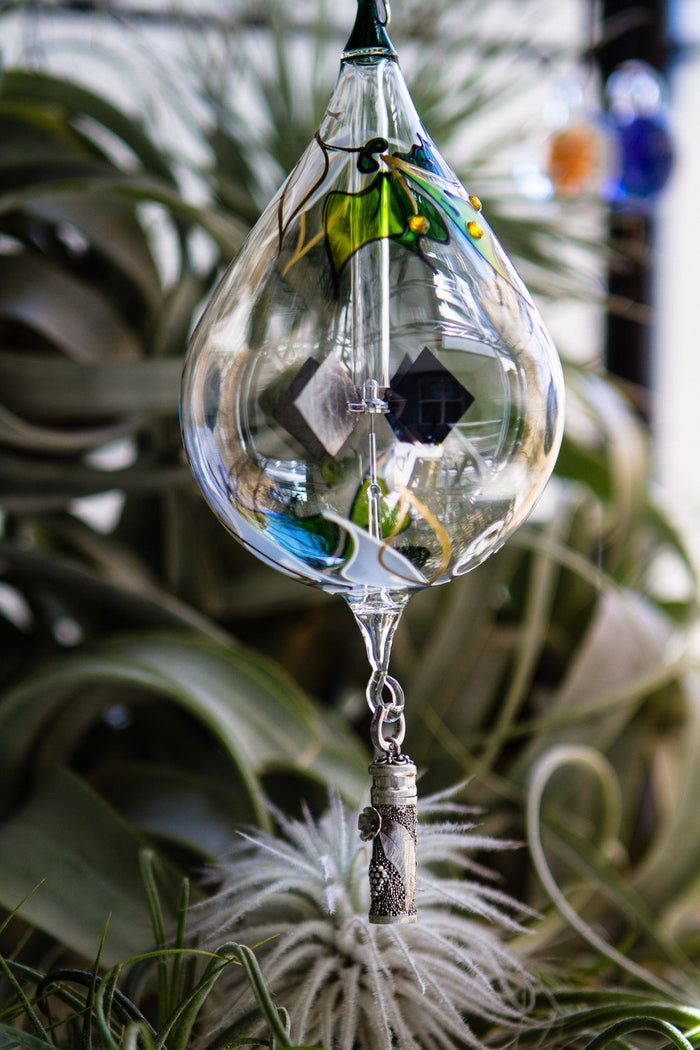 Glass radiometer ornament with a dangling sterling silver keepsake pendant and decorative tassel below.