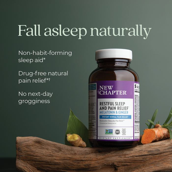 A bottle of New Chapter Restful Sleep and Pain Relief, Melatonin & Ginger Sleep Supplement sits on a wooden surface with leaves and ginger roots, highlighting its natural, non-habit-forming sleep aid benefits.