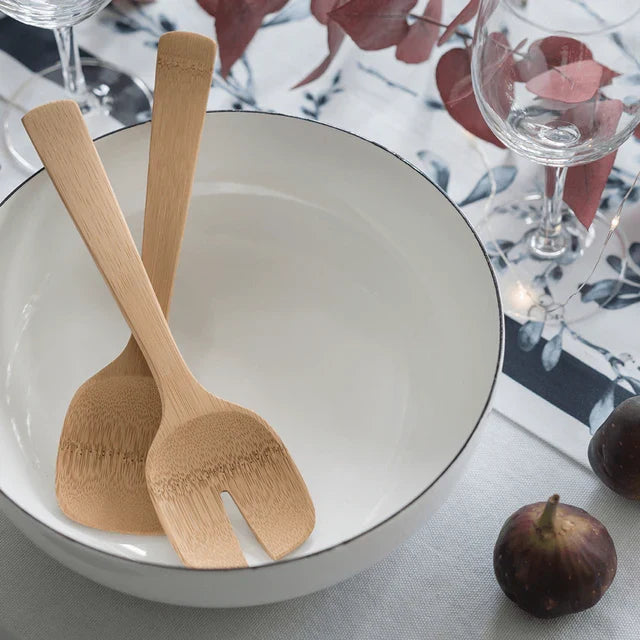 A white bowl holds Bambu's Short Bamboo Salad Servers. The table, set with wine glasses, figs, and a red-leaf-patterned cloth, adds an eco-friendly touch to dining.