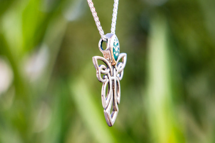 Sterling silver guardian angel pendant with a gold head and turquoise gemstone, suspended on a silver chain