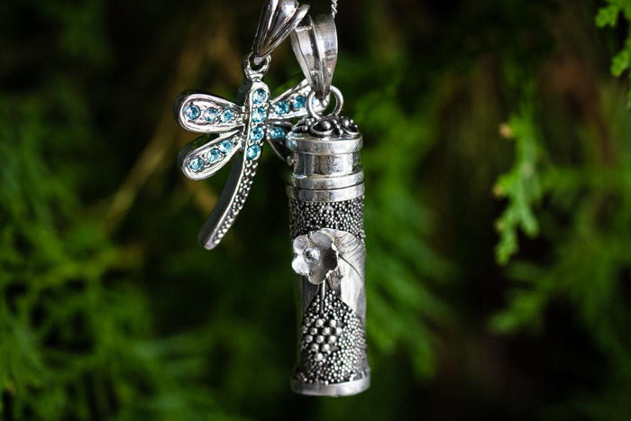 Sterling silver cremation pendant with raised flower detail and dragonfly charm for ash placement.