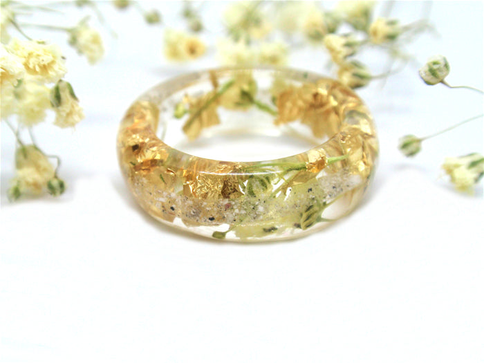 Crystal resin ring holding real yellow flower blooms and gold flakes with cremains
