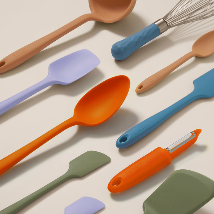The 10-Piece Best Sellers Kitchen Tool Set by GIR features assorted silicone utensils including colorful spatulas, a ladle, a whisk with a blue handle, and an orange peeler. Made from heat-resistant materials, these tools also highlight diverse colors and textures.