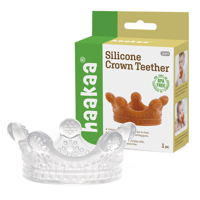 A clear silicone crown-shaped teether is beside its box, which features an orange Silicone Crown Toy labelled Haakaa 100% Food Grade Silicone Sensory Development Crown Teether, highlighting it as BPA-free with an image showing a baby using the product.