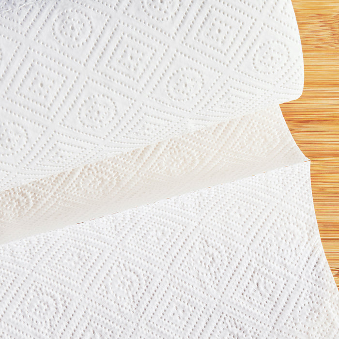 A roll of Grove Co.s Bamboo Paper Towels (140 sheets), featuring an embossed diamond pattern, is partially unrolled on a light wooden surface.