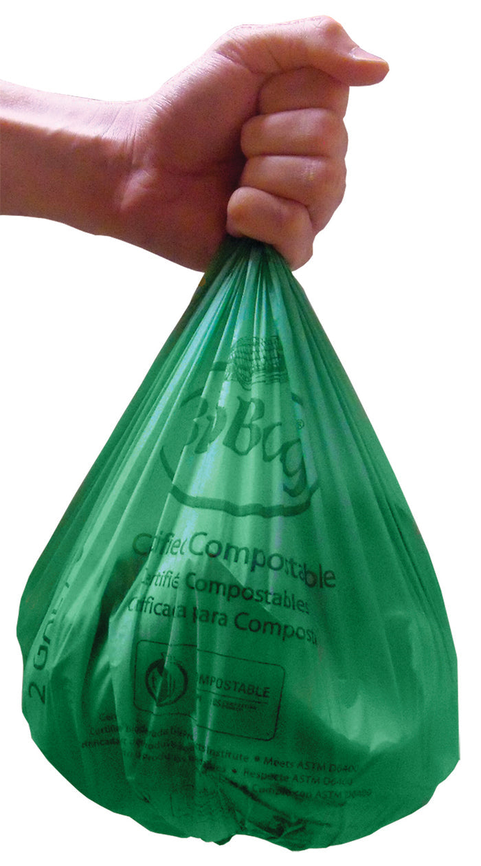 A hand grips a green BioBag Compostable Food Scrap Bag by the top. Slightly bulging, the bag features text and logos highlighting its eco-friendly qualities.