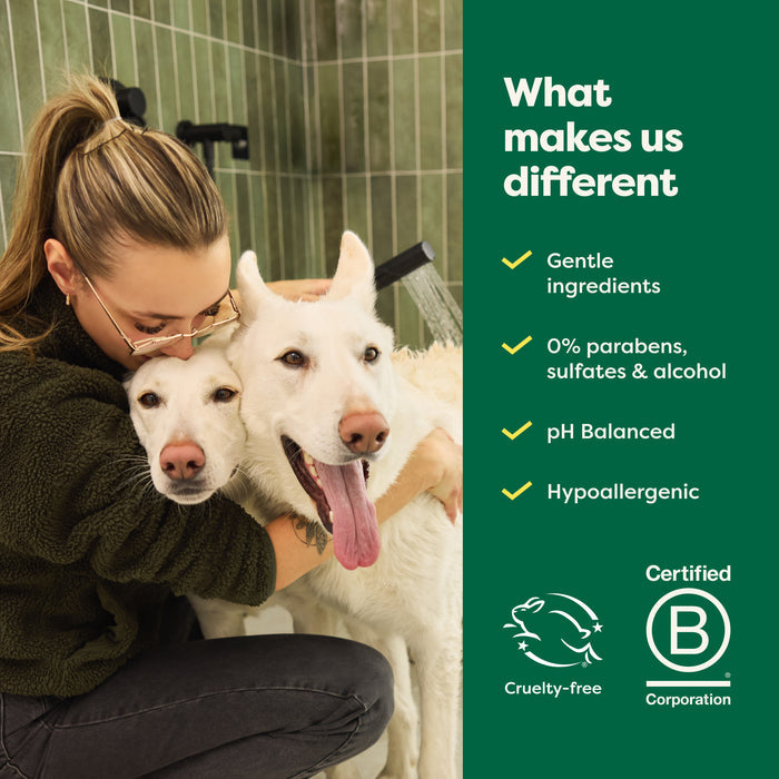 In a tiled bathroom, a person cuddles two white dogs while displaying Earth Rateds 3-in-1 Double Coat Dog Shampoo, enriched with jojoba seed oil. The product boasts gentle ingredients with no parabens, sulfates, or alcohol, is pH balanced and hypoallergenic, cruelty-free, and certified by B Corporation.