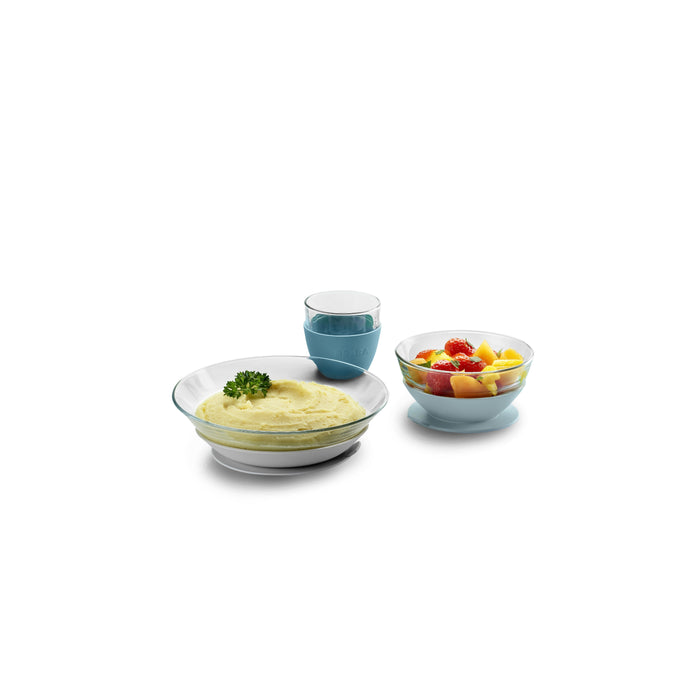 Three BEABA glass bowls: one filled with parsley-garnished mashed potatoes, another with mixed fruit, and a small one with blueberry yogurt. They are elegantly displayed against a white background.