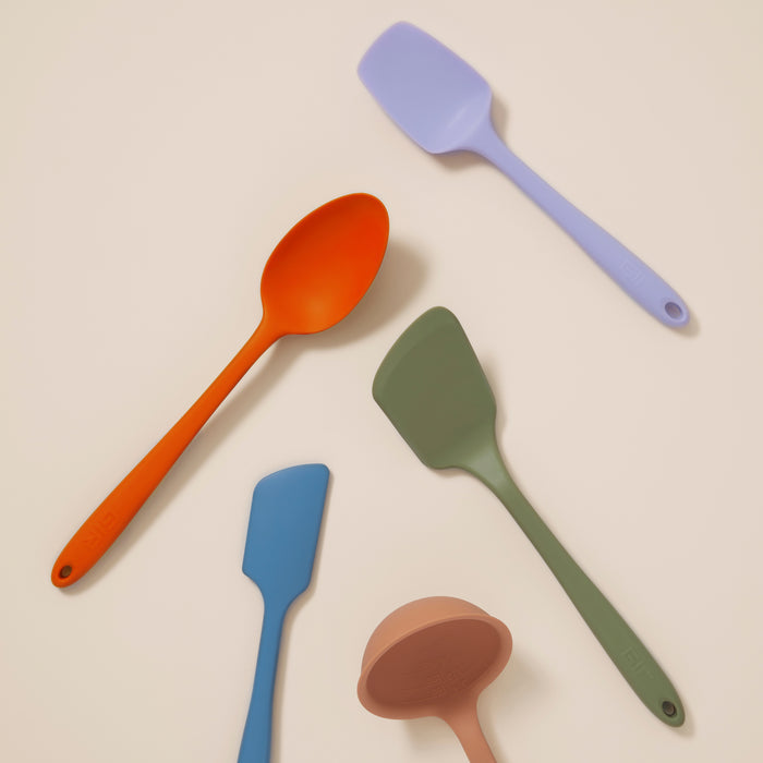The 5-Piece Ultimate Tool Set by GIR showcases assorted silicone cooking tools, like spatulas and spoons, on a neutral background. Featuring orange, lavender, green, blue, and pink colors, these heat-resistant utensils combine style and functionality for any kitchen.