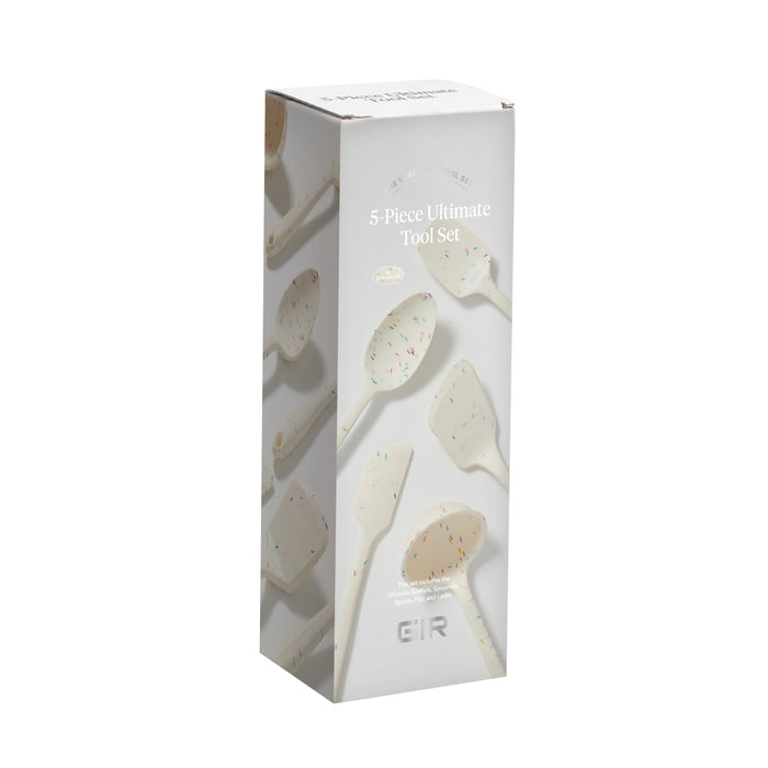 A rectangular box of the 5-Piece Ultimate Tool Set from GIR features heat-resistant kitchen utensils made from pharmaceutical-grade silicone. The light-colored box displays images of white utensils with colorful specks, and GIR is visible at the bottom.