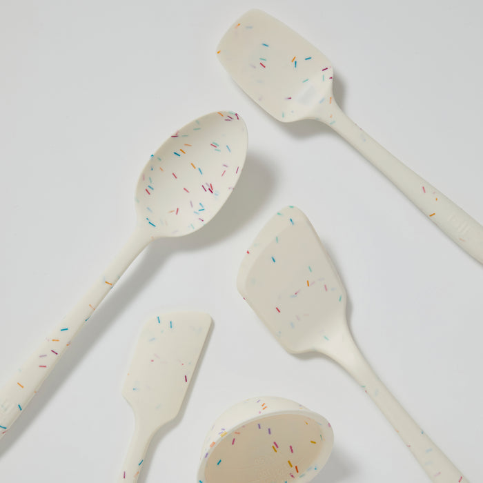 The 5-Piece Ultimate Tool Set by GIR features five white kitchen utensils made from pharmaceutical-grade silicone with colorful sprinkle patterns, including a spoon, spatula, and measuring cup. Arranged on a white background, they offer playful design and heat-resistant properties.