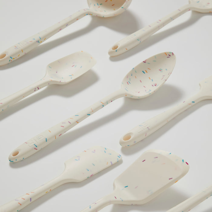 The GIR 5-Piece Ultimate Tool Set includes white silicone spoons and spatulas with a sprinkle pattern of colorful specks in blue, orange, yellow, and purple, arranged on a light surface. Each utensil is heat-resistant.