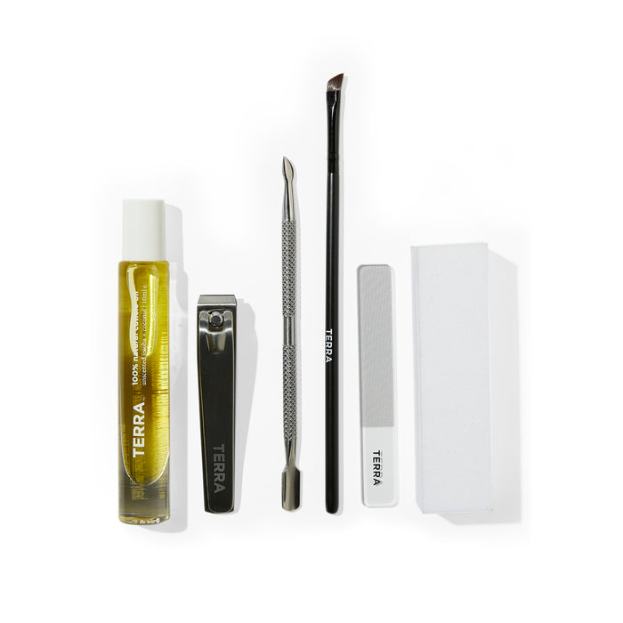 The 7-Piece Manicure Kit by Terra Beauty Bars includes nail clippers, a cuticle pusher, an angled brush, a file, a buffer block, and yellow cuticle oil. All items are displayed on a white background.