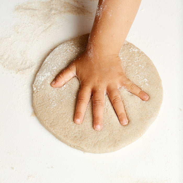 A childs hand presses dough on a white surface—ideal for crafting beach treasures or sand casting with your A Day at the Beach Set by Elseware Unplug.