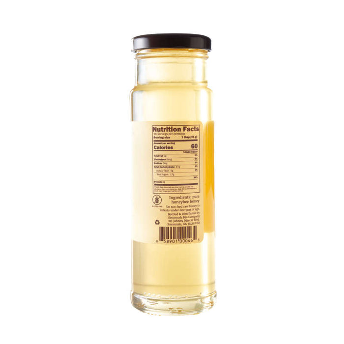 A tall, clear jar of Savannah Bee Companys Acacia Honey showcases a nutrition label on the front, providing calorie and nutritional info for this smooth and glossy single-varietal honey known for its high fructose content.