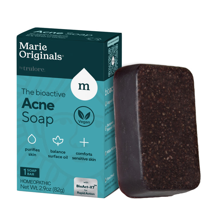 A dark brown rectangular bar of Marie Originals Acne Control Soap sits beside a teal and white box, featuring natural salicylic acid, vegan ingredients, and detoxifying clay to help balance surface oil and purify skin.