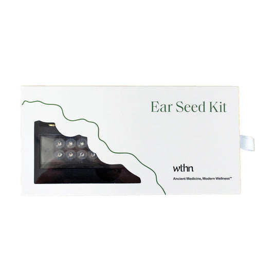The image shows a white box labeled Acupressure Crystal Ear Seed Kit with ear seeds in a small cutout. Green decorative lines accentuate the design, showcasing the brand WTHN and the tagline Ancient Medicine, Modern Wellness, emphasizing acupressure and pain relief benefits.