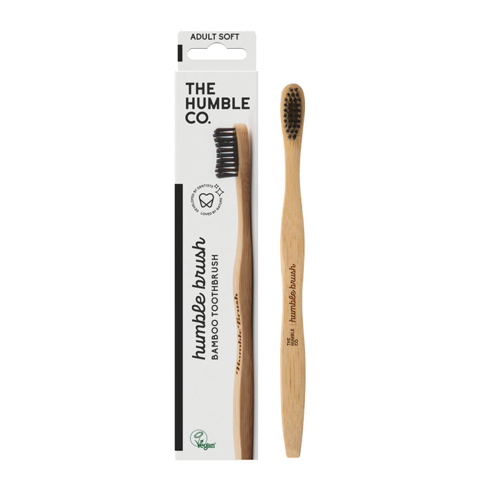 The Adult Bamboo Toothbrush - Soft from The Humble Co. features dentist-approved black nylon bristles and is elegantly presented in a white box with green and black text displaying the logo and the soft designation.