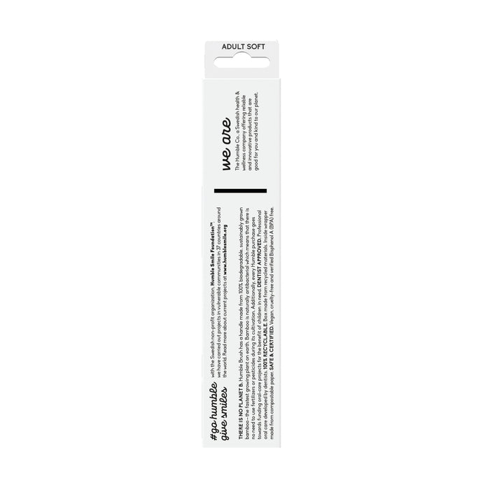 Back of a white toothbrush box labeled Adult Bamboo Toothbrush - Soft by The Humble Co., showcases the brands philosophy. It features dentist-approved nylon bristles and a minimalist design, with a small logo and website link at the bottom.