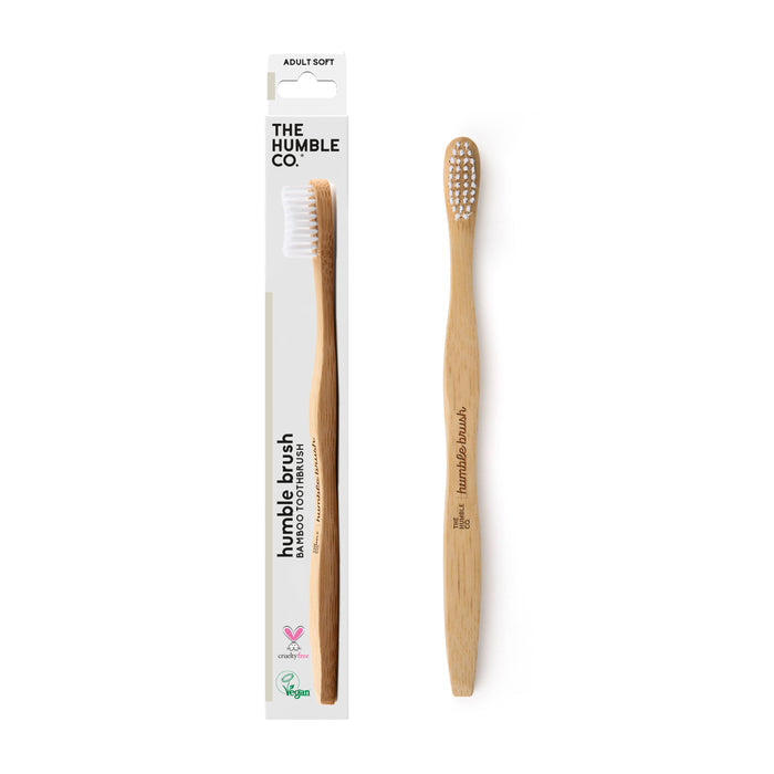 An Adult Bamboo Toothbrush - Soft by The Humble Co. is shown beside its packaging. With white nylon bristles, its crafted from sustainable materials and dentist-approved for quality and eco-friendliness in your daily routine.