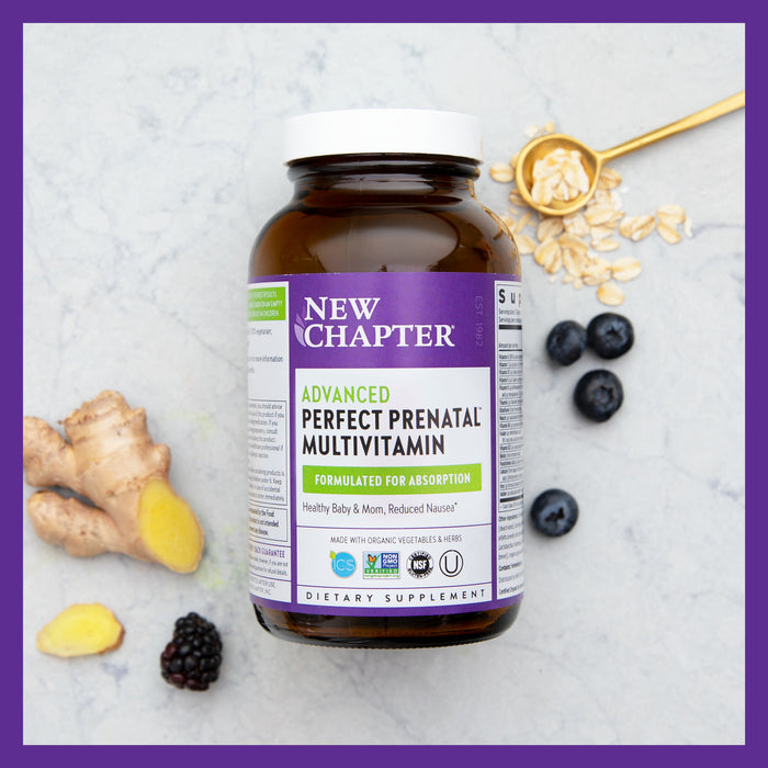 A bottle of New Chapter Advanced Perfect Prenatal™ Multivitamin for Healthy Baby & Mom rests on marble, surrounded by ginger, blueberries, blackberries, and rolled oats. The label emphasizes Formulated for Absorption with organic prenatal vitamins like methylfolate to support fetal development.
