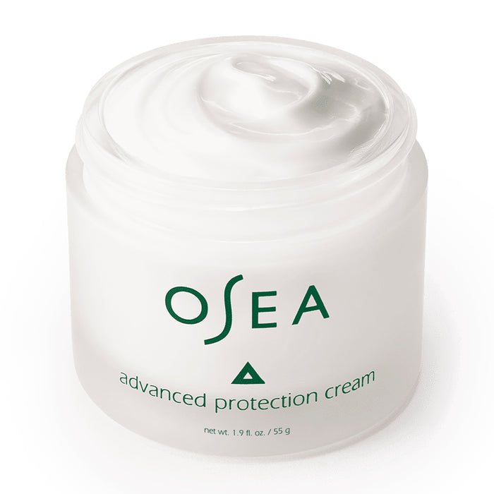 An open white jar of OSEA Advanced Protection Cream, infused with Undaria seaweed, reveals its creamy texture. This 1.9 oz (55 g) jar is filled with marine moisture for a luxurious boost to your skin.