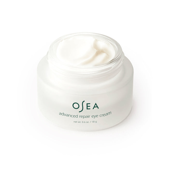 Set against a white background, the OSEA Advanced Repair Eye Cream, in a frosted glass jar with visible white cream, offers anti-aging benefits. The label states OSEA advanced repair eye cream, net 0.6 oz / 18 g.