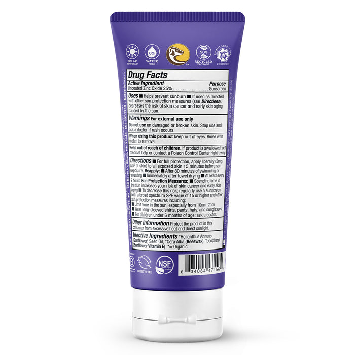 A purple tube of Badger Balms Adventure Sport Mineral Sunscreen Cream - SPF 50 stands backward, with detailed product info in white text, including drug facts, usage directions, warnings, and ingredients. The NSF certification mark and zinc oxide are visible near the bottom. Reef-friendly formula included.