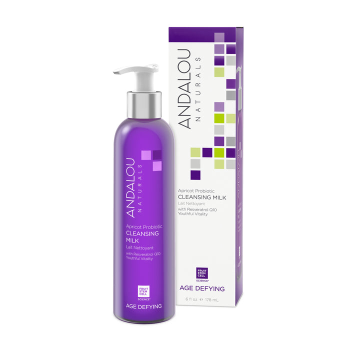 A purple bottle of Andalou Naturals Age Defying Apricot Probiotic Cleansing Milk, ideal for dry skin, stands beside its matching box. The elegant packaging displays the brand logo, product name, and vibrant square designs. Enriched with age-defying antioxidants for gentle cleansing.