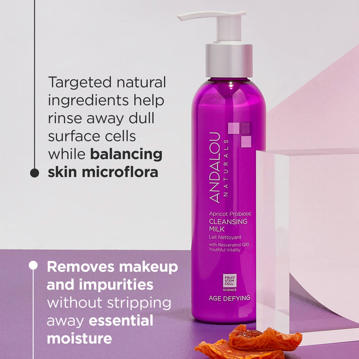 A bottle of Andalou Naturals Apricot Probiotic Cleansing Milk against a minimalist background. Text highlights its benefits: rinses away dull surface cells, balances skin microflora, and removes makeup while preserving moisture.