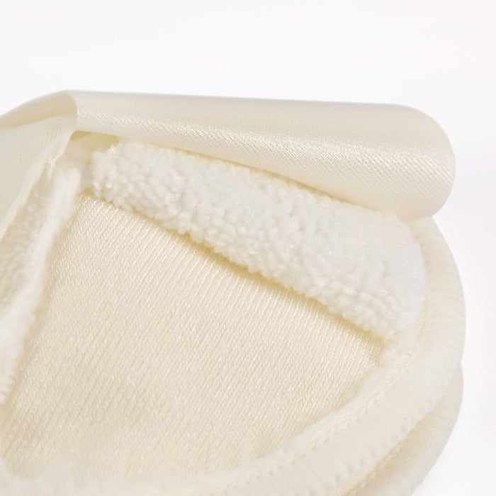 A close-up of Haakaas All-Day Reusable Nursing Pads shows the soft, cream-colored microfiber fabric with a smooth outer layer and fluffy, bamboo-like inner core. The folded edge highlights the contrasting textures typical of these pads.