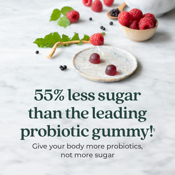 Two red All-Flora Probiotic + Prebiotic Raspberry Gummies by New Chapter on a marble plate with fresh raspberries. Text: 55% less sugar than leading probiotic gummies! Support digestive health with more probiotics, not more sugar.