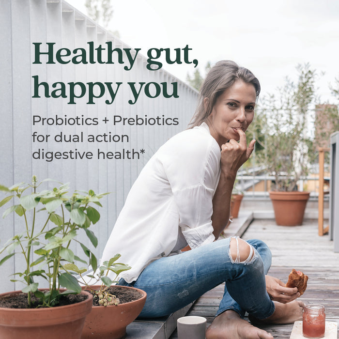 A woman sits on a wooden deck, eating and smiling, surrounded by potted plants. Text reads: “Healthy gut, happy you. New Chapter All-Flora Probiotic + Prebiotic Gummies in Raspberry flavor support dual-action digestive health.”.