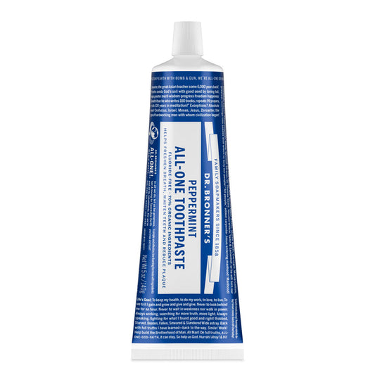 A blue and white tube of Dr. Bronners All-One Toothpaste stands upright with the cap on, displaying its label. This natural toothpaste is fluoride-free and features the Peppermint variety branding.