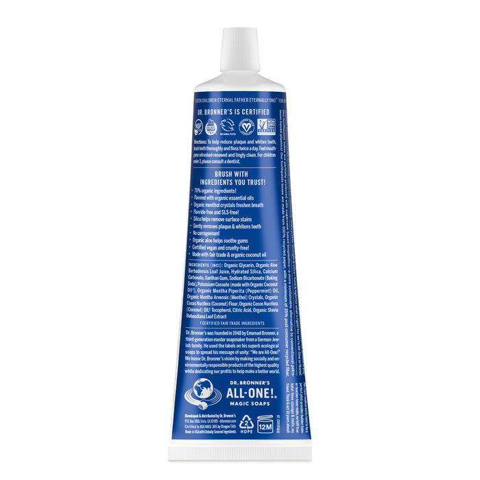 A blue and white tube of Dr. Bronners All-One Toothpaste stands upright, showing its back label with ingredients, certifications, and product details listed in white text.