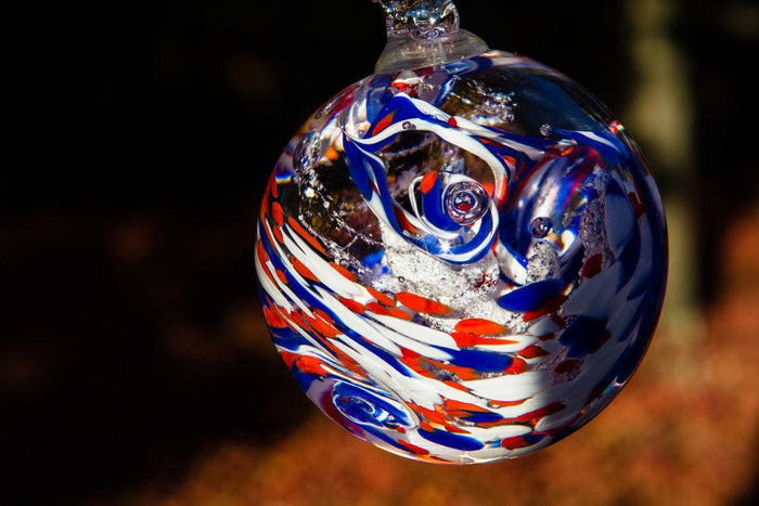 American Confetti Orb suspended from a clear hook with red white and blue swirls and ashes infused.