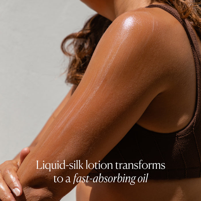 A person in a brown top applies OSEA Anti-Aging Body Balm to their shoulder. Text reads: This liquid-silk body balm transforms to a fast-absorbing oil, improving skin elasticity.