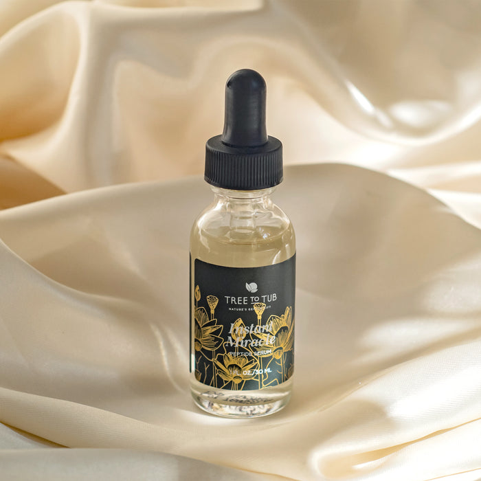 A dropper bottle labeled Tree To Tub and Anti-Aging Peptide & Niacinamide Serum rests elegantly on shiny cream-colored fabric, adorned with floral illustrations, exuding sophistication.