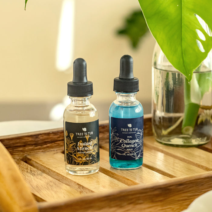 Two serums, Anti-Aging Peptide & Niacinamide Serum for Face by Tree To Tub, sit with dropper caps on a wooden tray. A large green leaf and a glass of water complete the serene backdrop.