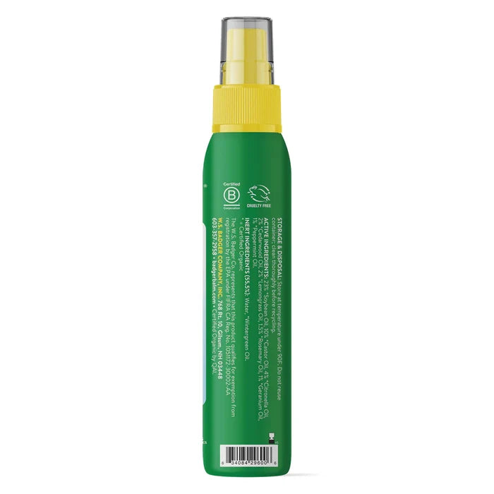 A green Anti-Bug Shake & Spray bottle by Badger Balm with a yellow cap, shown from the back, displays white ingredient details, certification icons near the top, and is labeled as an organic insect repellent with citronella lemongrass.