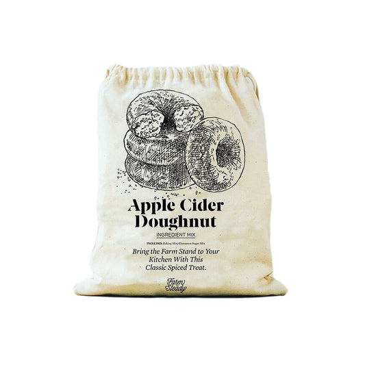 The cream-colored cloth bag from FarmSteady features a vintage-style illustration with the text Apple Cider Doughnut Baking Mix. Ideal for those who love homemade treats, these delicious doughnuts are dusted with cinnamon sugar.