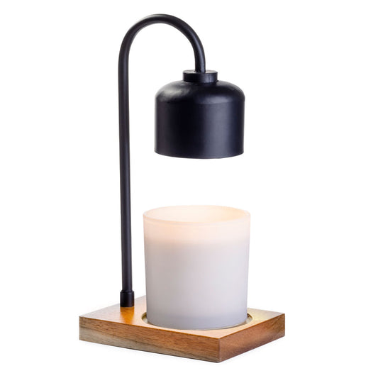 Introducing the Arched Candle Warmer Lamp by Candle Warmers Etc., a modern masterpiece featuring a sleek black metal arc and chic cylindrical metallic shade. It hovers over a glowing white candle on a stylish wood base, blending simplicity and functionality perfectly.
