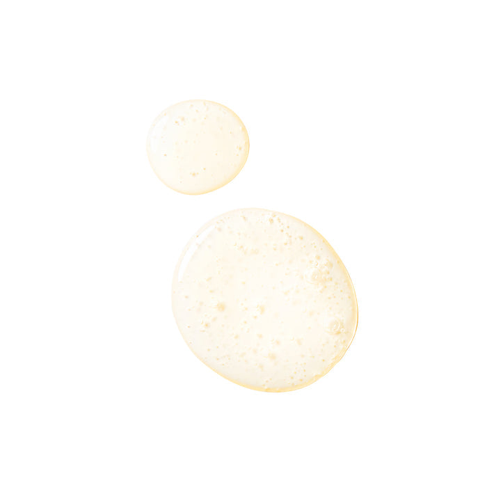 Two beige liquid droplets of varying sizes, akin to Tree To Tubs Argan Oil Hydrating Shampoo for Dry Scalp & Hair, lie on a white background. The larger droplet slightly overlaps the smaller one, both featuring a glossy texture with tiny air bubbles.
