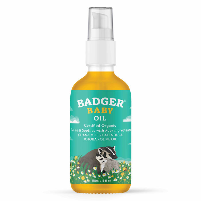 A 118 ml bottle of Badger Balm Baby Oil with a pump dispenser has a forest and sky design, featuring a badger, flowers, and text stating Certified Organic, Chamomile, Calendula, Jojoba, Olive Oil. This gentle moisturizer is made with organic ingredients.