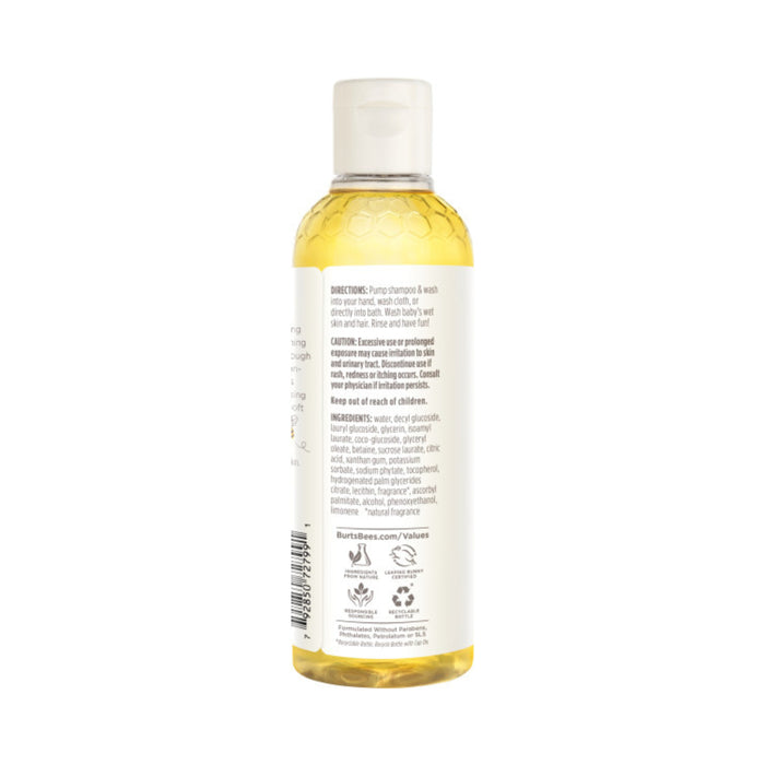 The Burts Bees Baby™ Shampoo and Wash is housed in a clear plastic bottle with yellow liquid, featuring a white flip-top cap. The back label includes directions and natural ingredients, with icons for tear-free formula and more product attributes at the bottom.