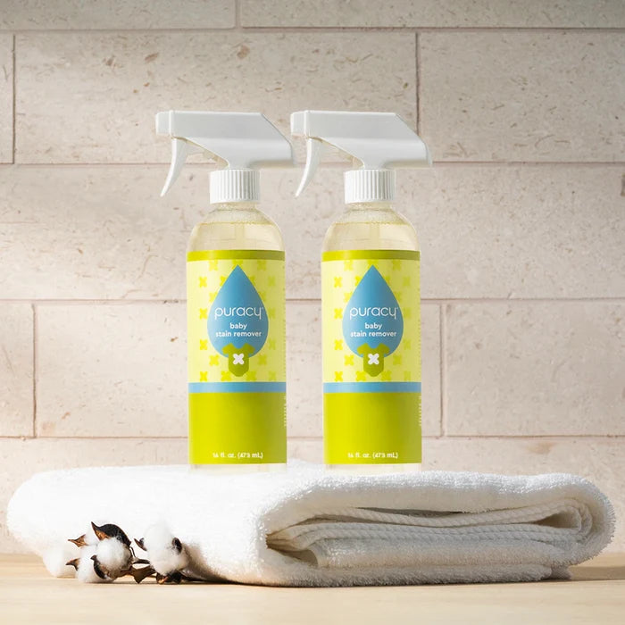 Two Baby Stain Remover bottles on a white towel with cotton flowers; hypoallergenic formula.