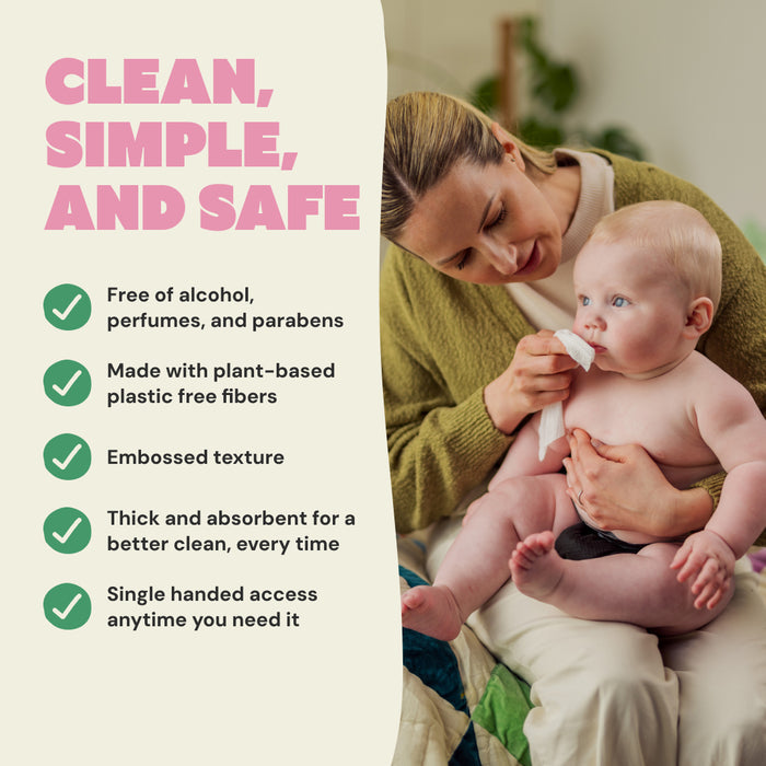A woman wipes a baby's mouth while holding the child on her lap. DYPER Baby Wipes for Sensitive Skin are plant-based, hypoallergenic, alcohol-free, thick, absorbent, embossed, and offer single-handed access.